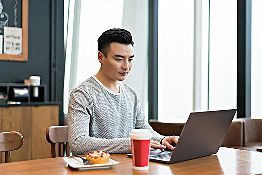 年轻男子在餐厅使用电脑