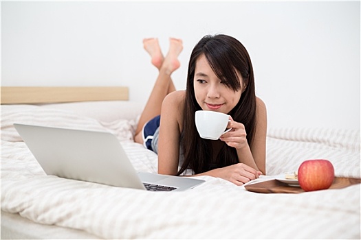 亚洲女性,看,笔记本电脑,吃早餐,床上