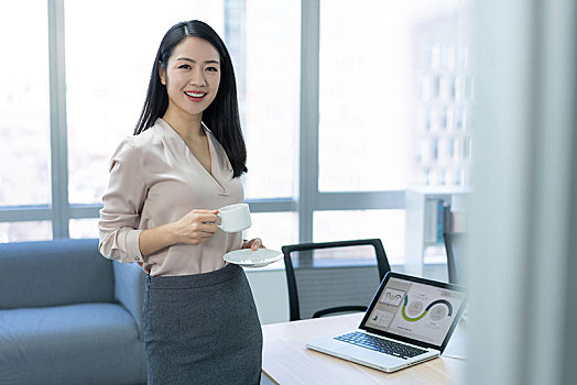 年輕商務女士在辦公室喝咖啡