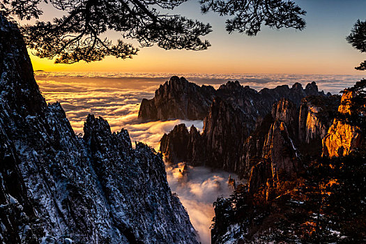 中国安徽黄山风景区,冬日雪后放晴,夕阳映照山崖云雾飘渺宛若仙境