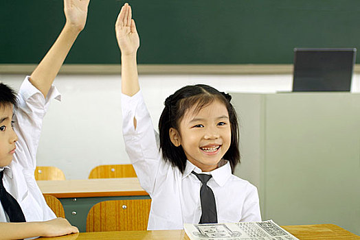 课堂上高举手臂的两个小学生