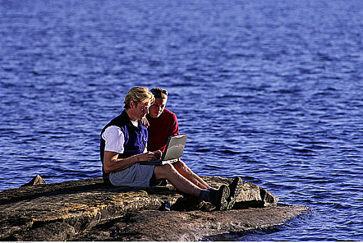 坐,夫妇,岩石上,湖,使用笔记本,电脑,安大略省,加拿大