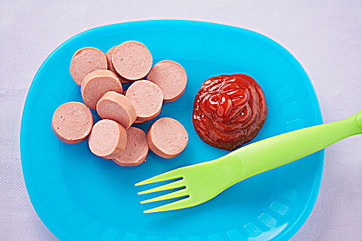 切片,热狗,番茄酱,塑料制品,叉子,蓝色背景,盘子