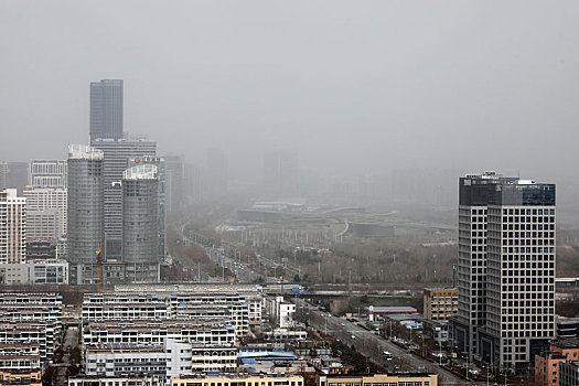 山东省日照市,大雾沙尘冷空气接连来袭,远处城市建筑灰蒙蒙一片