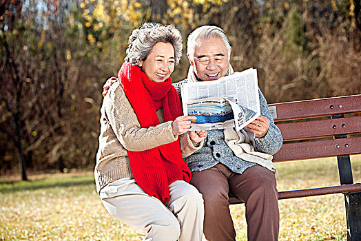 坐在椅子上拿报纸的老夫妻