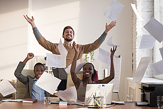 商务人士,兴奋,高兴,微笑,抛起,纸,文件,空中,坐,办公室,书桌,握手,抬臂,成功,团队,概念