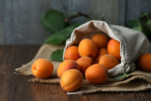 木桌上的杏放在粗麻布袋子里
