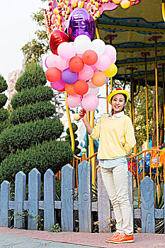 年轻女人牵着气球在游乐园