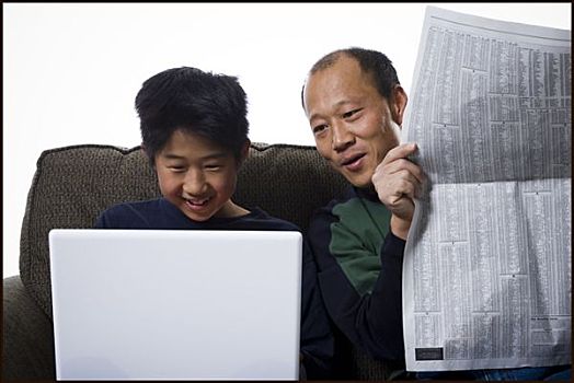 特写,父亲,拿着,报纸,儿子,笔记本电脑