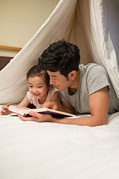 小女孩和爸爸在床上看书
