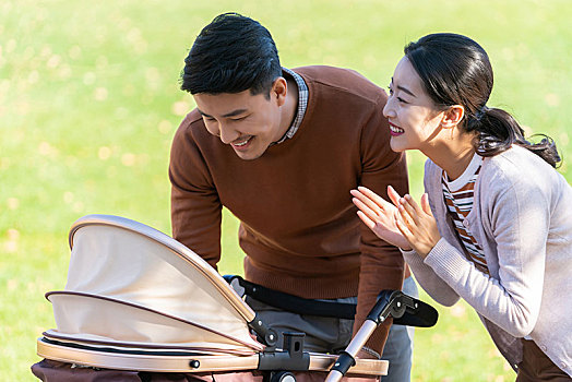 年轻夫妻推着婴儿车散步