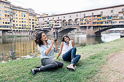 女同性恋伴侣,坐,阿尔诺河,堤岸,正面,维奇奥桥,拿着,数码相机,微笑,佛罗伦萨,托斯卡纳,意大利