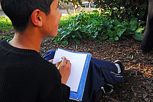 algeria,alger,midsection,of,a,schoolboy,writing,islamic,text,on,book