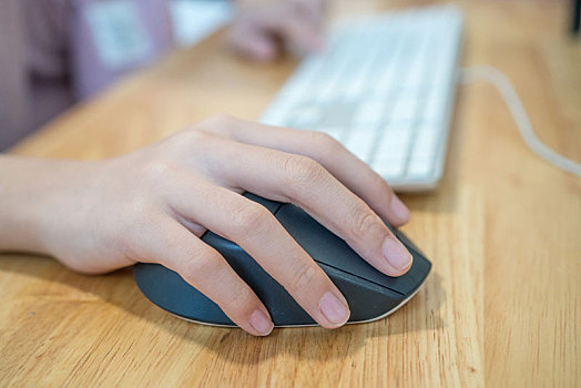 女孩的手放在电脑鼠标和键盘上正在工作