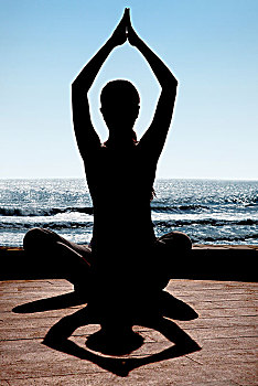 坐在海边练瑜伽的女士