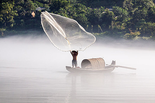 渔夫在飘渺晨雾的湖泊中打鱼