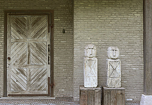 两个,塑像,木质,方形底座,靠近,木门,砖墙