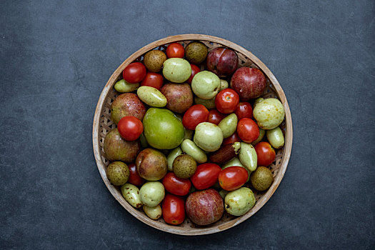 各种各样的新鲜水果,枣,樱桃番茄,龙眼,李子,在一个深灰色的背景