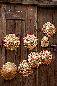 重庆巴南区丰盛古镇街道门板上挂的手工艺品草帽