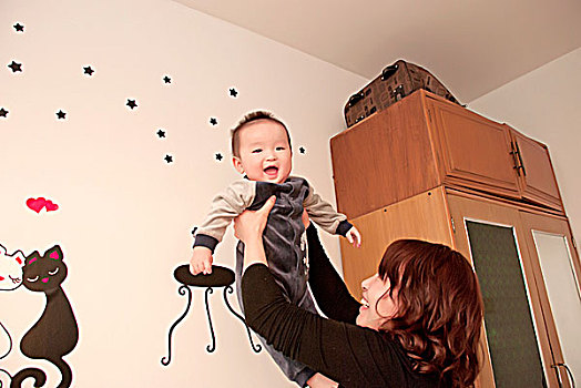 一名7个月大的男婴被母亲举了起来做游戏