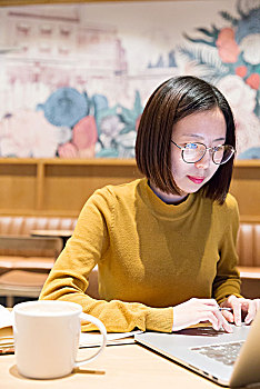 年轻的女性在咖啡馆上网工作