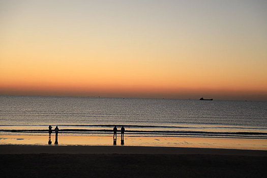 海边绚丽霞光染红天际线,游客惊叹忙打卡拍照