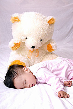 女婴和玩具熊睡觉