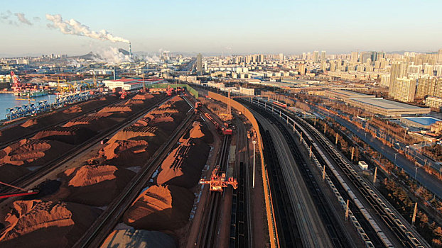 山东省日照市,航拍晨曦里的铁矿石堆场,火车往来穿梭一片繁忙景象