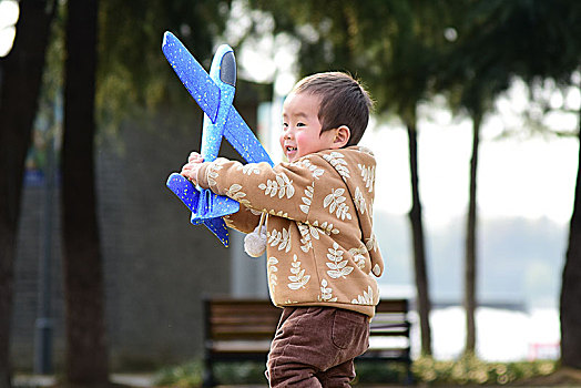秋天草坪上玩飞机的小男孩