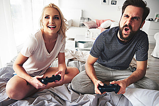 坐,夫妇,床,拿着,电脑,手柄,玩,电脑游戏