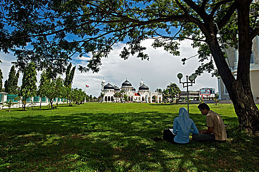 indonesia,sumatra,banda,aceh,couple,under,tree,in,front,of,baiturrahman,grand,mosque,mesjid,raya