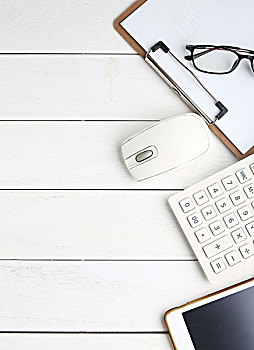眼镜,平板电脑,鼠标和计算器放在白色桌面上,商务,金融,投资等概念