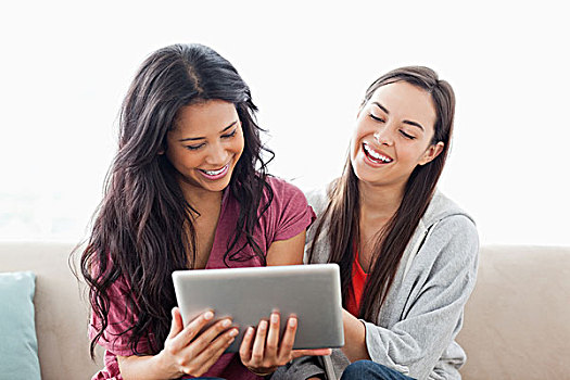 两个女人,笑,坐,沙发,一起,看,平板电脑
