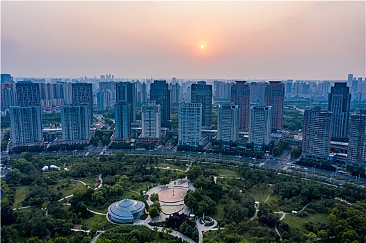 航拍河南省郑州市郑东新区cbd城市环形建筑群,夕阳下的红白花公园及商务内环商务外环高层建筑群