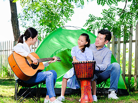 幸福的三口之家在公园弹吉他