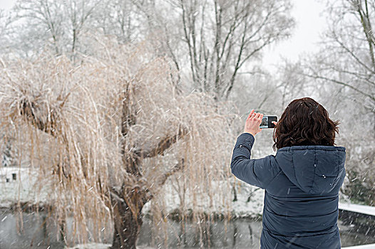 雪中用手机拍照的女子