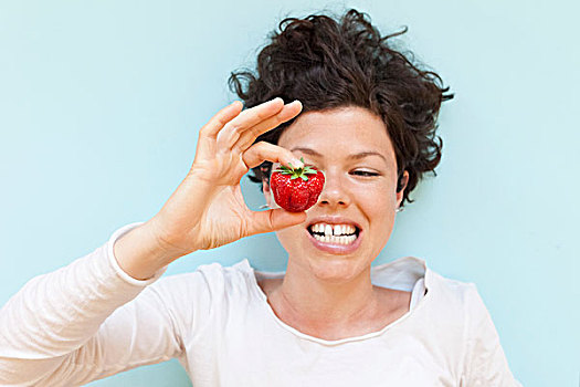 女人,咬牙,拿着,草莓,上方,蓝色背景