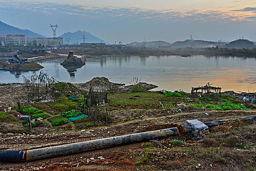 管道,房屋,炊烟,截流,拖拉机,汽车,推土机,池塘,河流,两岸,高压线,高压塔,电力,黄昏,清洁能源,绿色电力