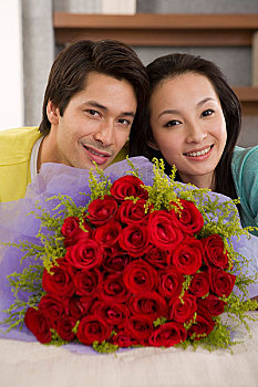 一对年轻的夫妻趴在床上看着面前摆放的鲜花