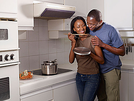 夫妇在厨房,女人拿着木制汤匙,微笑的