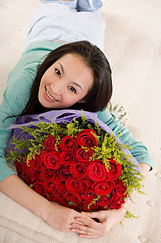 一个女人抱着一束鲜花趴在床上