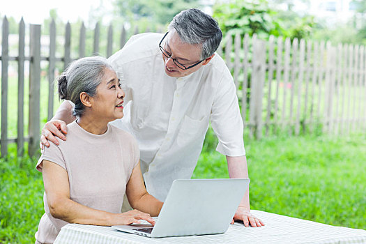 幸福的老年夫妇在户外使用电脑上网