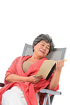中老年女人坐在沙滩椅上看书