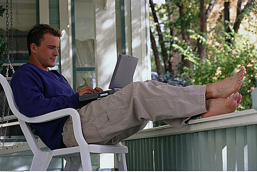 男人,坐,椅子,门廊,使用笔记本,电脑