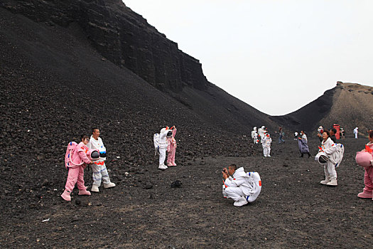 内蒙古火山口游客穿宇航服拿国旗拍照,宛若登陆外星球