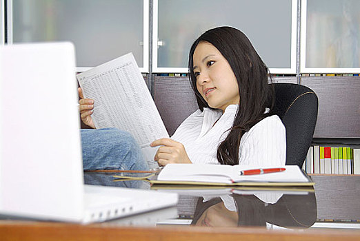 坐在电脑前看文档的年轻女人