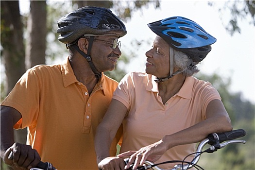 活力老人,情侣,戴着,自行车头盔,马球衫,坐,自行车,公园,面对面,微笑