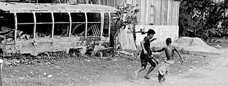 group,of,asian,children,playing,soccer,in,front,burned,bus