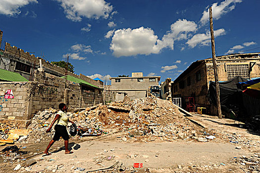 haiti,port,au,prince,woman,walking,on,street,with,ruins