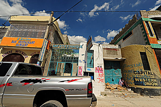 haiti,port,au,prince,4x4,car,parked,in,front,of,ruined,commercial,building,and,homeless,woman